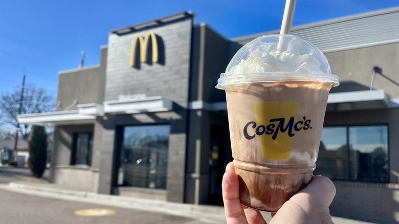 Hand holding McDonald's Chocolate Milkshake in front of storefront