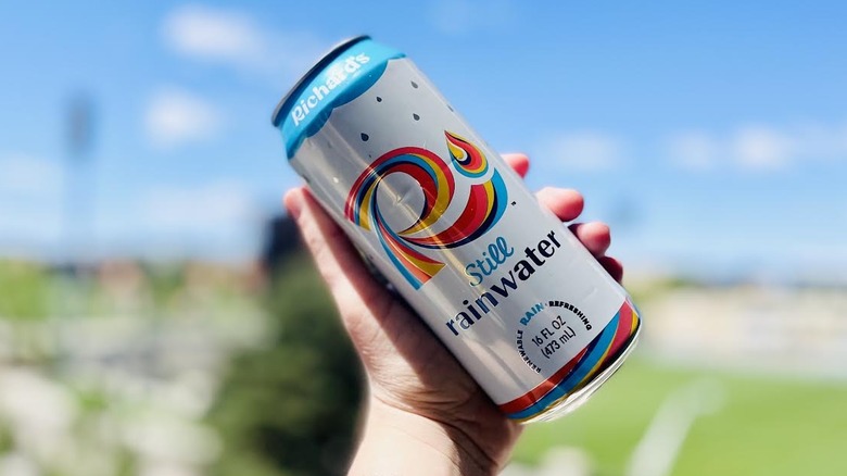 Hand holding can of Richard's Still Rainwater