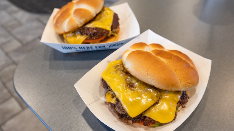 Two Culver's cheeseburgers sit in cardboard containers on a gray countertop