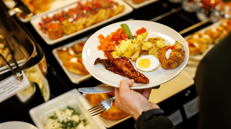 Guest picks up foods at the hotel breakfast buffet