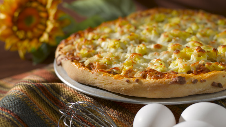 Breakfast pizza with scrambled eggs, hash browns, and cheese