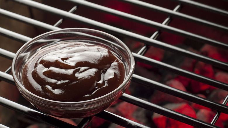 Closeup of a bowl of Lexington Dip barbecue sauce sits on a grill grate