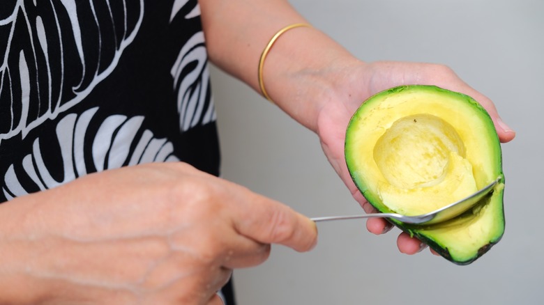 Person scooping avocado flesh with spoon