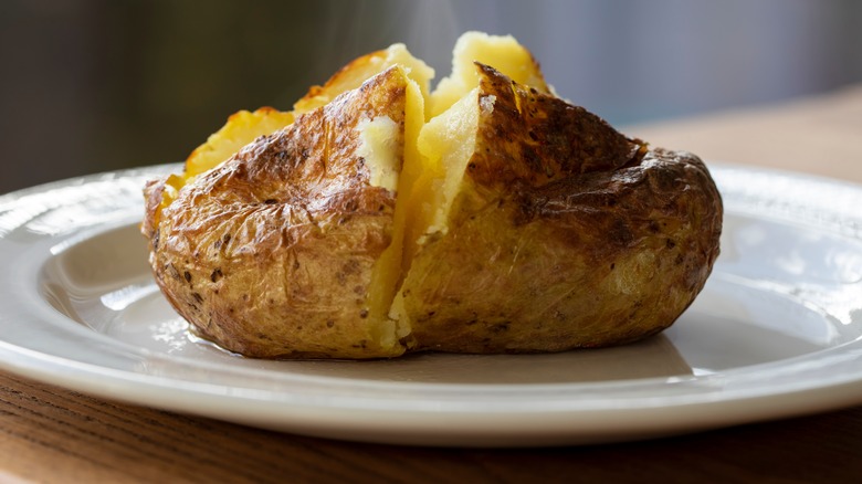 A plain baked potato on a plate ready to be topped