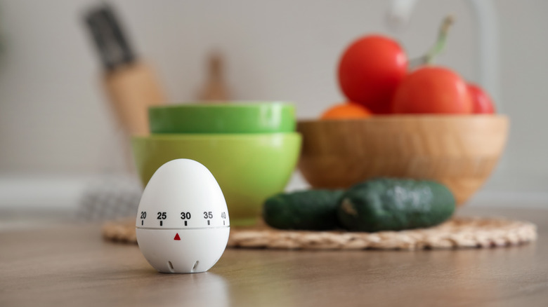 an egg timer on a table with vegetables