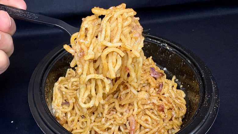 carbonara ramen on fork over black bowl
