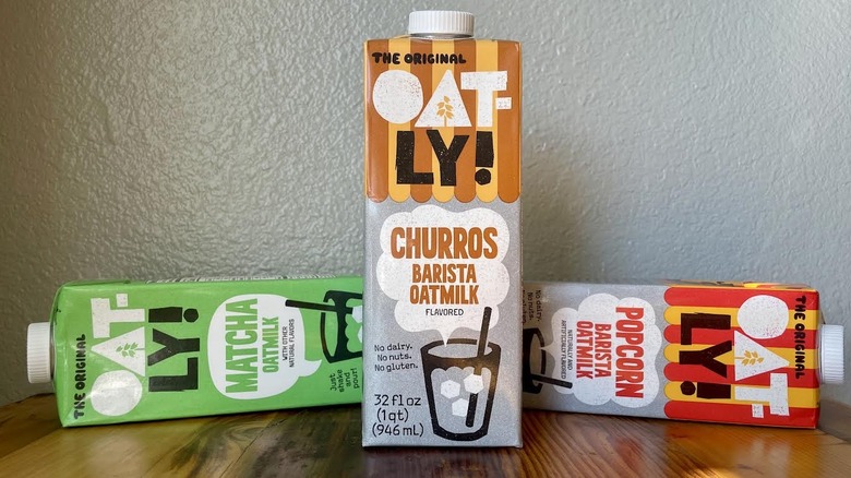 Cartons of Oatly oat milk in various flavors on a wooden table top