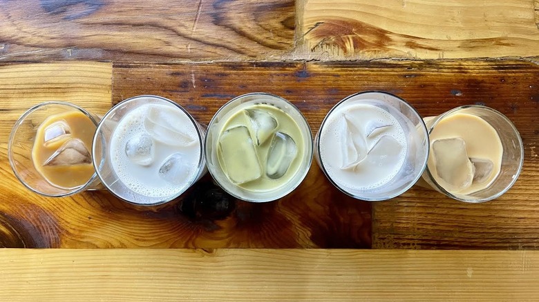 Overhead view of five glasses filled with oat milk on ice