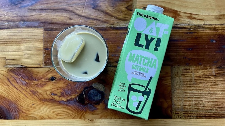 Overhead view of Oatly Matcha Latte Oatmilk with a glass of it on ice