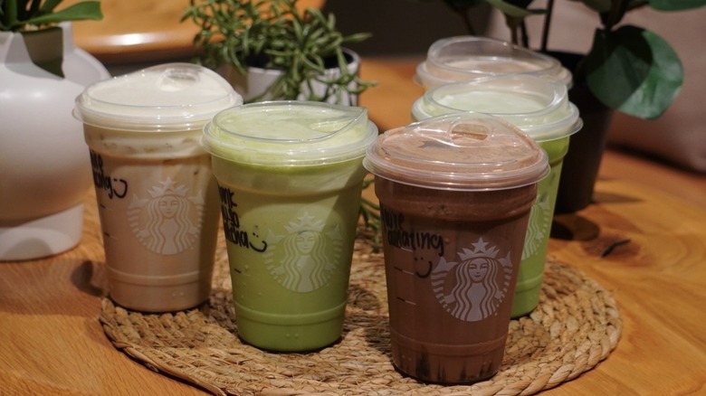 Overhead view of Protein Cold Foam Drinks and Protein Lattes on a woven placemat in front of plants