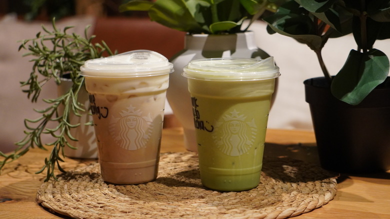 Iced Vanilla Cream Protein Latte and Iced Banana Cream Protein Matcha on a woven placemat in front of plants