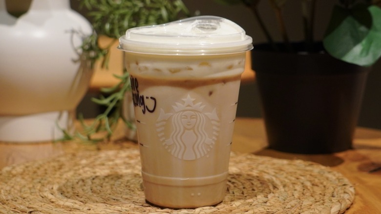 Iced Vanilla Cream Protein Latte on a woven placemat in front of plants