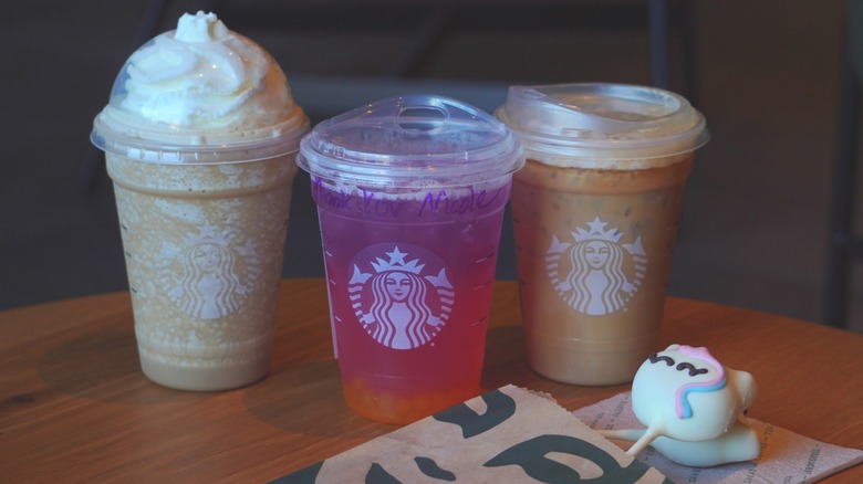 Starbucks' Horchata Frappuccino, Tropical Butterfly Lemonade Refresher, and Iced Horchata Shaken Espresso (left to right) behind two Unicorn Cake Pops.