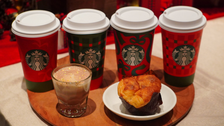 Overhead view of Starbucks Cinnamon Pull-Apart Bread, Caramel Miso Hot Chocolate, and holiday cups on a wooden tray