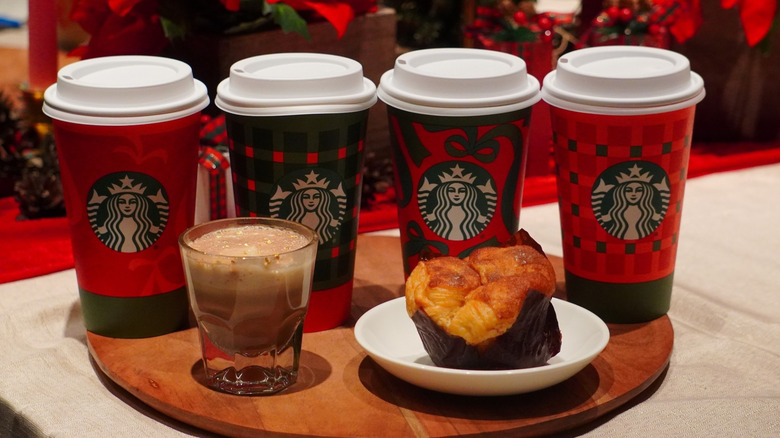 Starbucks Caramel Miso Hot Chocolate and Cinnamon Pull-Apart Bread in front of Starbucks holiday coffee cups