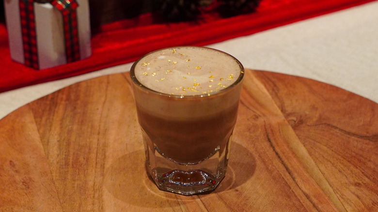 Starbucks Caramel Miso Hot Chocolate on a wooden tray in front of wrapped gifts