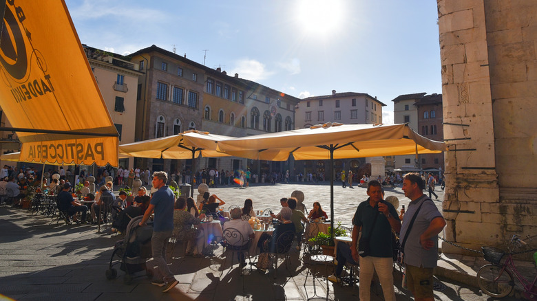Cafe-goers sit under umbrellas in an outside seating area on the Il Campo in Siena