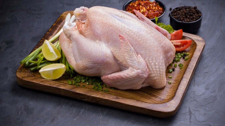 Whole raw chicken with lemon wedge