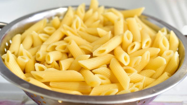 cooked penne pasta in colander