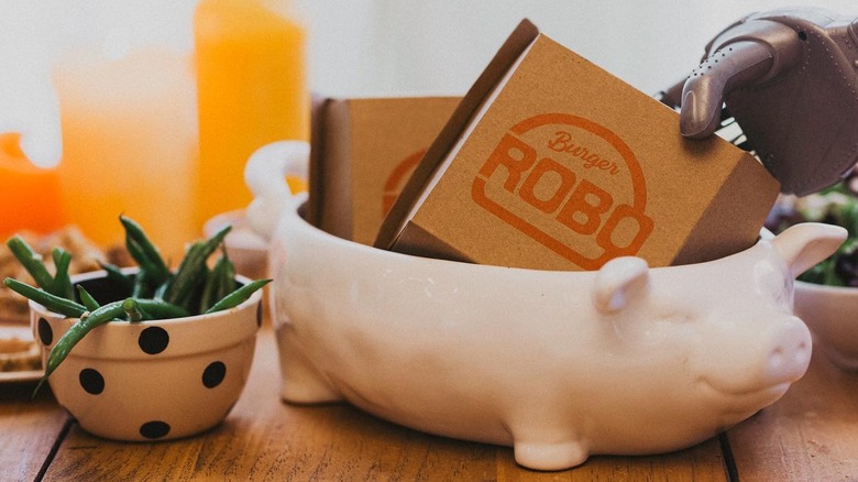RoboBurger boxes in dish held by a robot hand