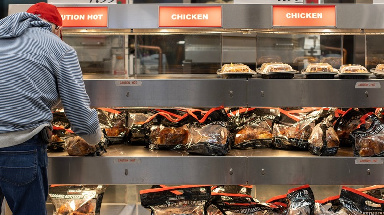 A man choosing a grocery store rotisserie chicken