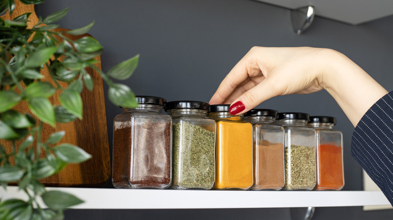 A female hand choosing from various jars of seasoning