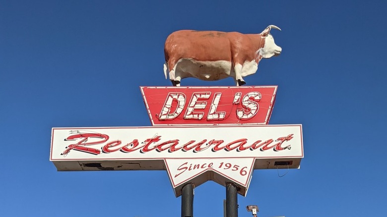 The sign of Del's Restaurant which has a large cow on top of it