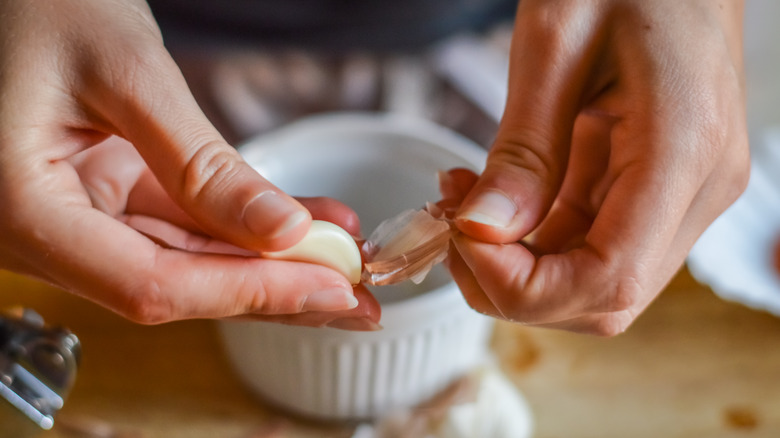 Hands peeling garlic clove