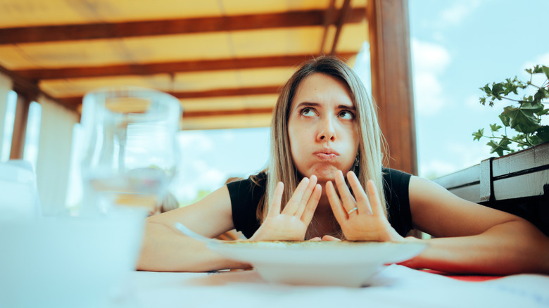 Woman pushing her dish away at a restaurant
