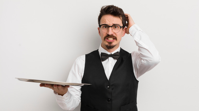 A male waiter looks scared or anxious
