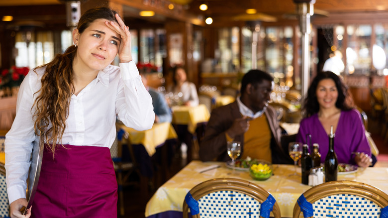 A waitress holds her head while working