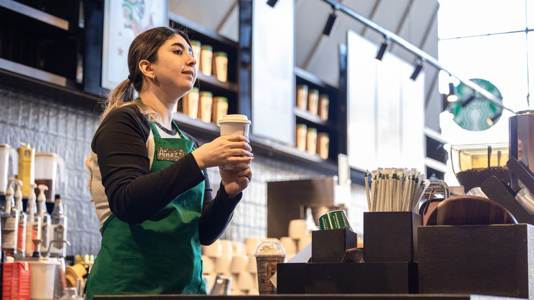 Starbucks barista holding drink.