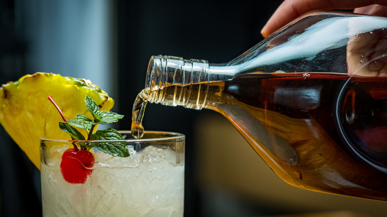 Pouring rum into tropical cocktail