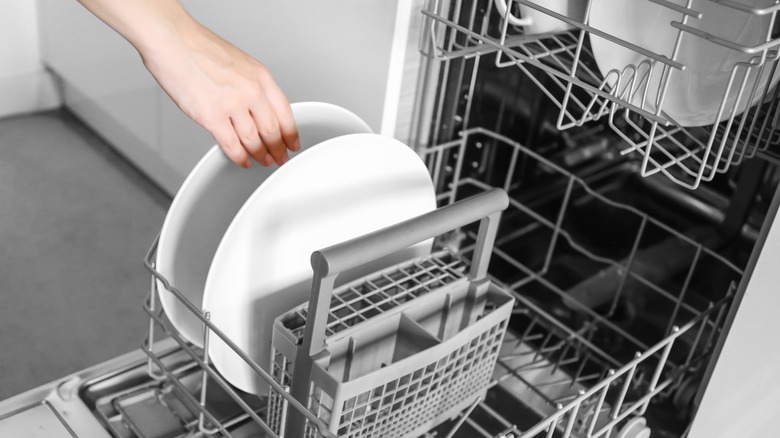A hand loading the dishwasher