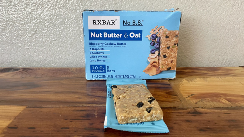 Box of RX Bar Nut Butter & Oat Blueberry Cashew Butter protein bars with one unwrapped