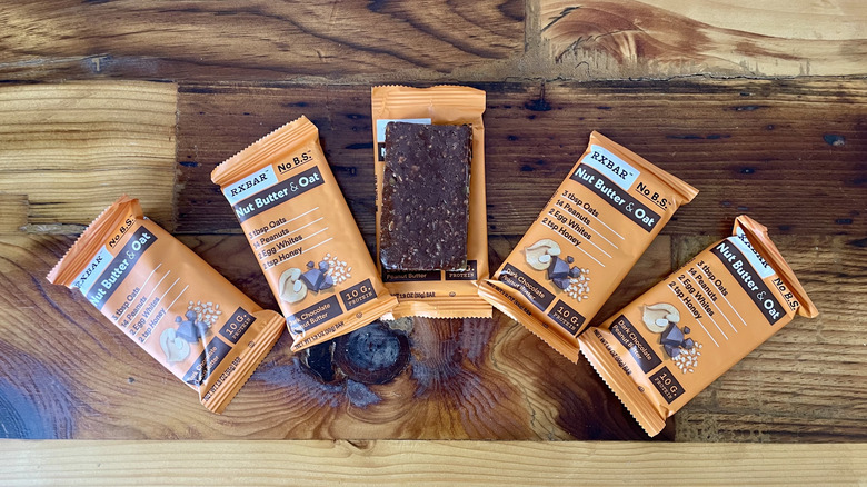 Several RX Bar Nut Butter & Oat Dark Chocolate Peanut Butter protein bars on a wooden tabletop