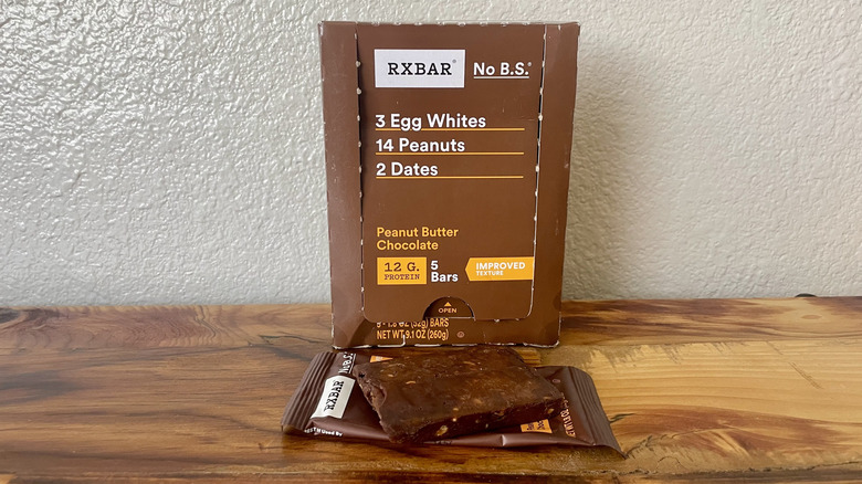 A box of RX Bar Peanut Butter Chocolate protein bars with one unwrapped