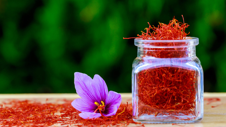 saffron in a jar with a purple flower next to it