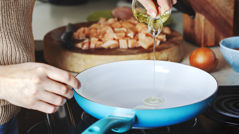 Person pouring oil into pan