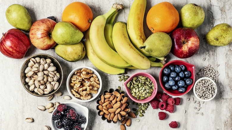 A variety of fruits and nuts sit on a marbled background