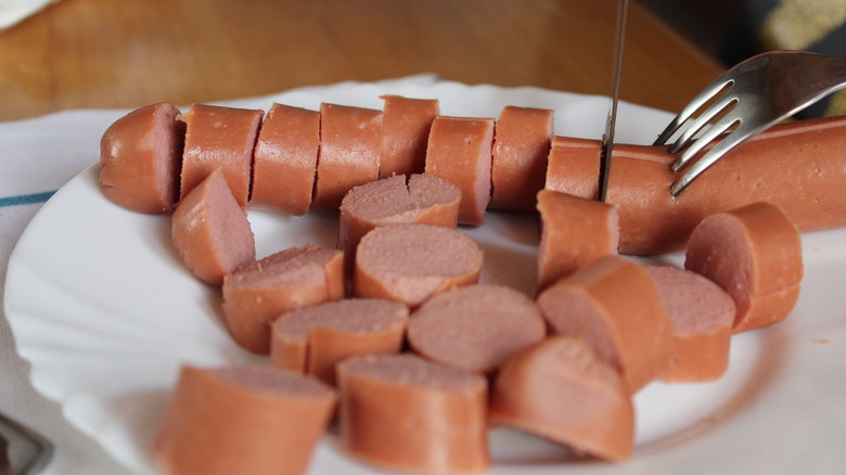 someone cutting up hot dogs