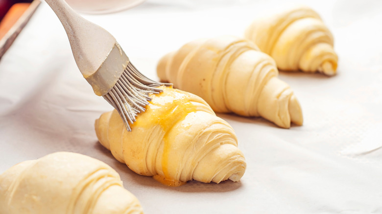 Brushing unbaked croissants with eggwash
