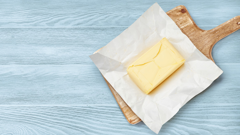 butter in wrapper on wooden board