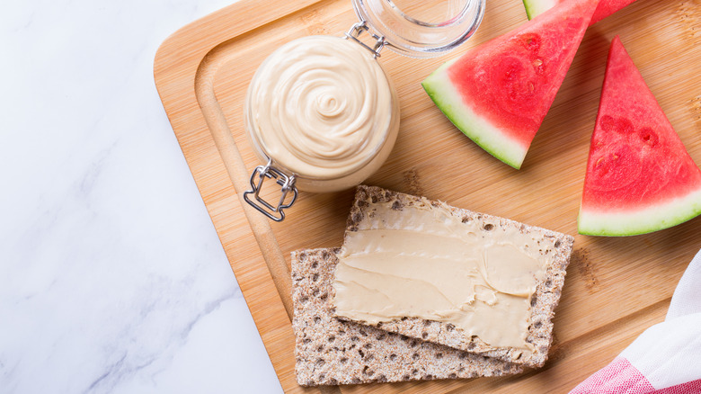 Jar of watermelon seed butter, crackers, and watermelon