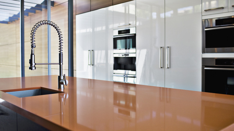 An orange countertop paired with glossy white cabinets in a home kitchen