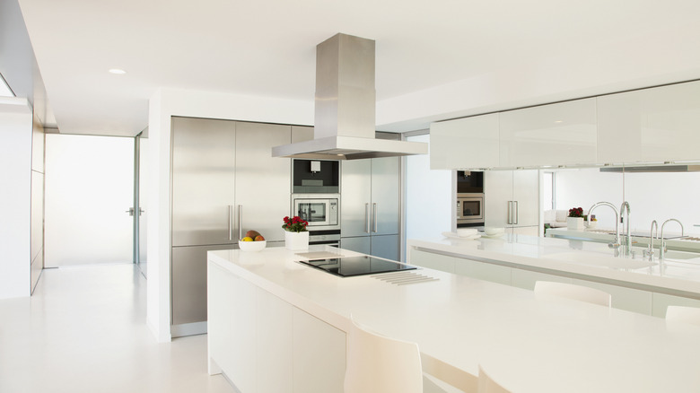 An empty white kitchen with large island and empty counters