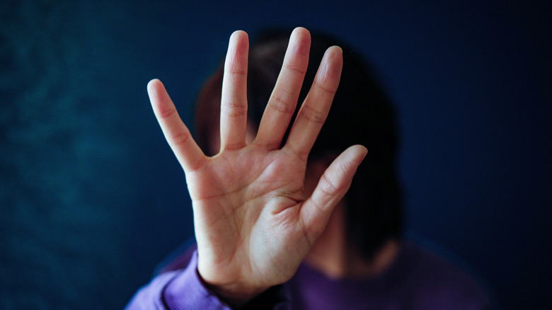 woman blocking face and demanding space with hand
