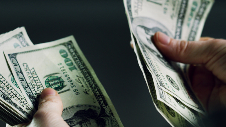 hands counting several hundred dollars