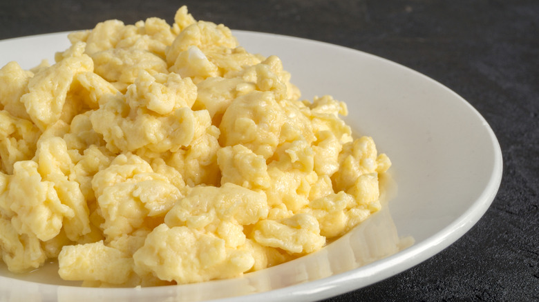 Scrambled eggs sit on a white plate.