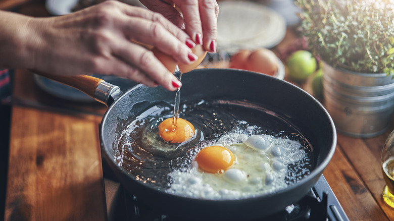 cracking eggs in a pan